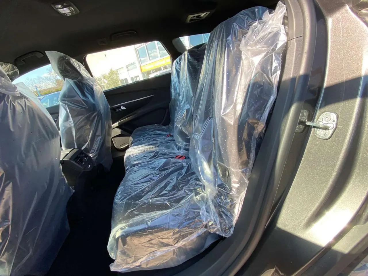 Vue côté gauche arrière du Peugeot 5008 gris platinium métal, sièges arrière protégés par housses plastiques.