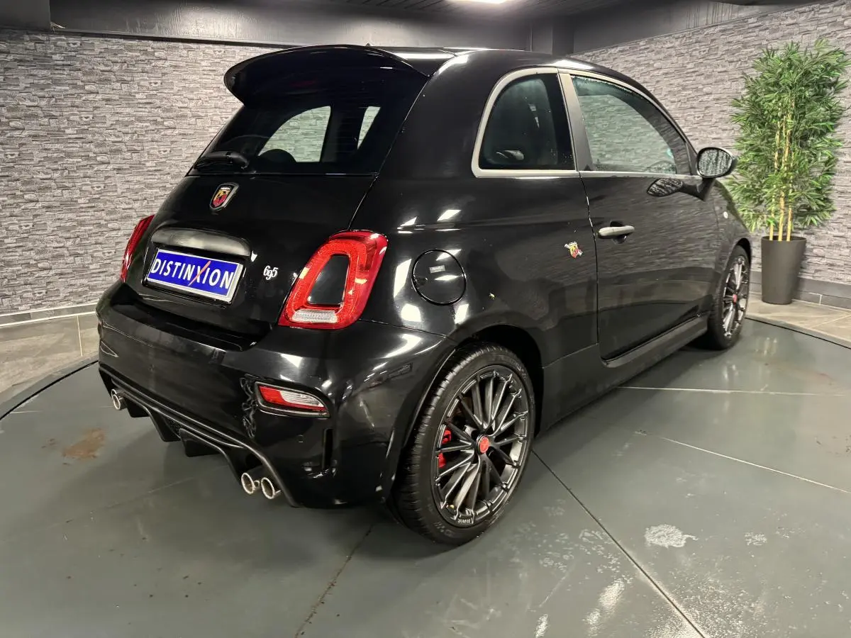 Vue 3/4 arrière droite de l'Abarth 595 Competizione noire avec jantes alliage et échappement quadruple chromé.