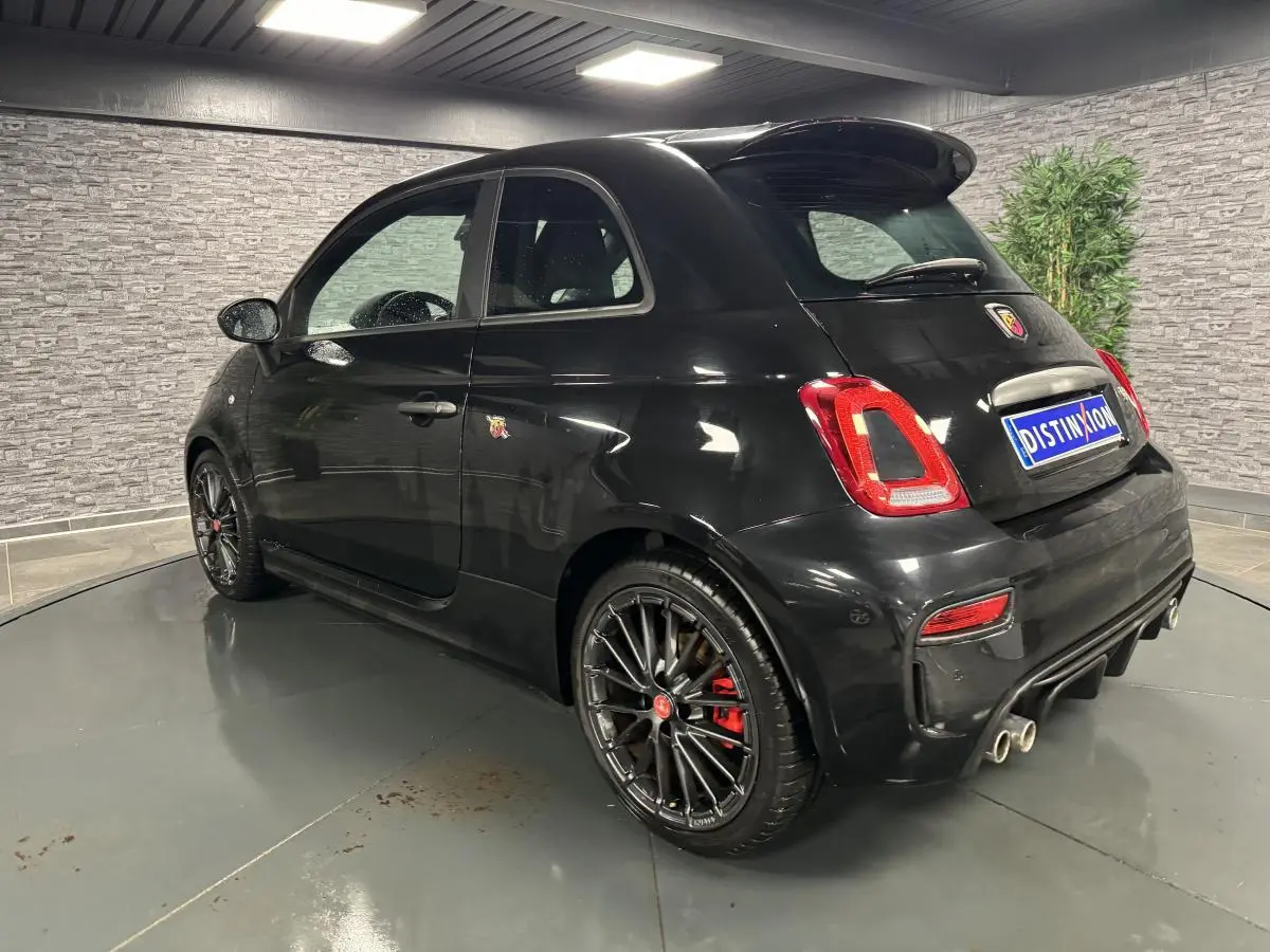 Vue 3/4 arrière droite de l'Abarth 595 Competizione noire avec jantes noires et échappement quadruple chromé.