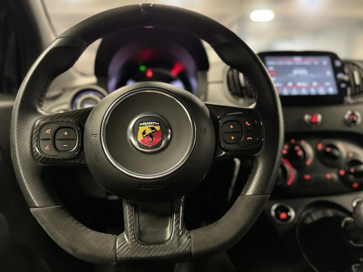 Volant cuir/alcantara avec logo Abarth au centre, tableau de bord et écran tactile 7'' vus de face à l'intérieur du véhicule.