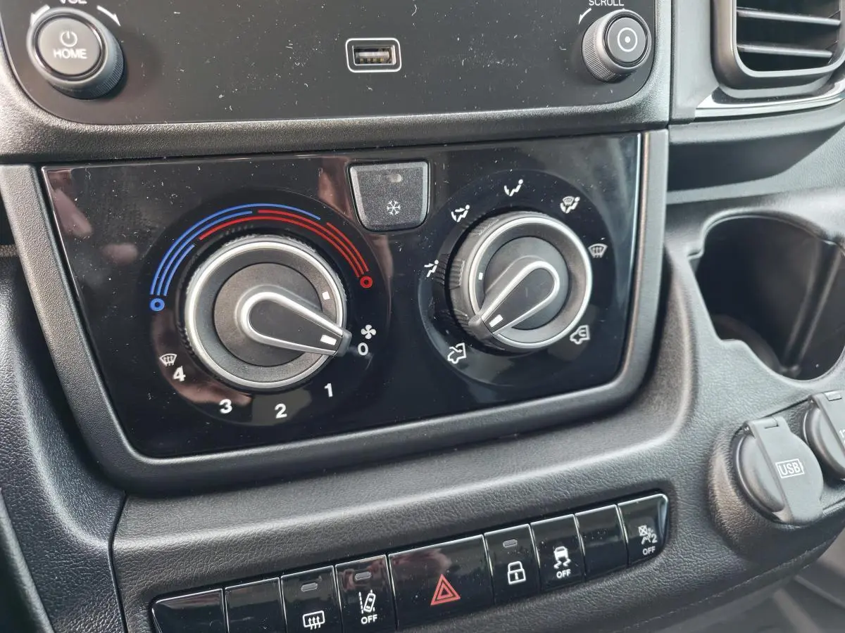 Gros plan sur la console centrale du Fiat Ducato Fourgon blanc, montrant les commandes de climatisation et les boutons de sécurité.