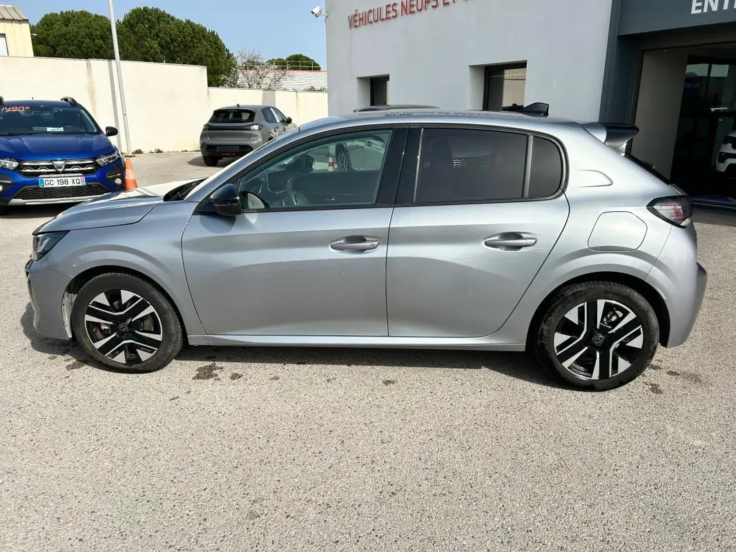 Vue de profil côté gauche d'une Peugeot 208 Hybrid 110 gris métallisé avec jantes noires et argentées, modèle 2024.
