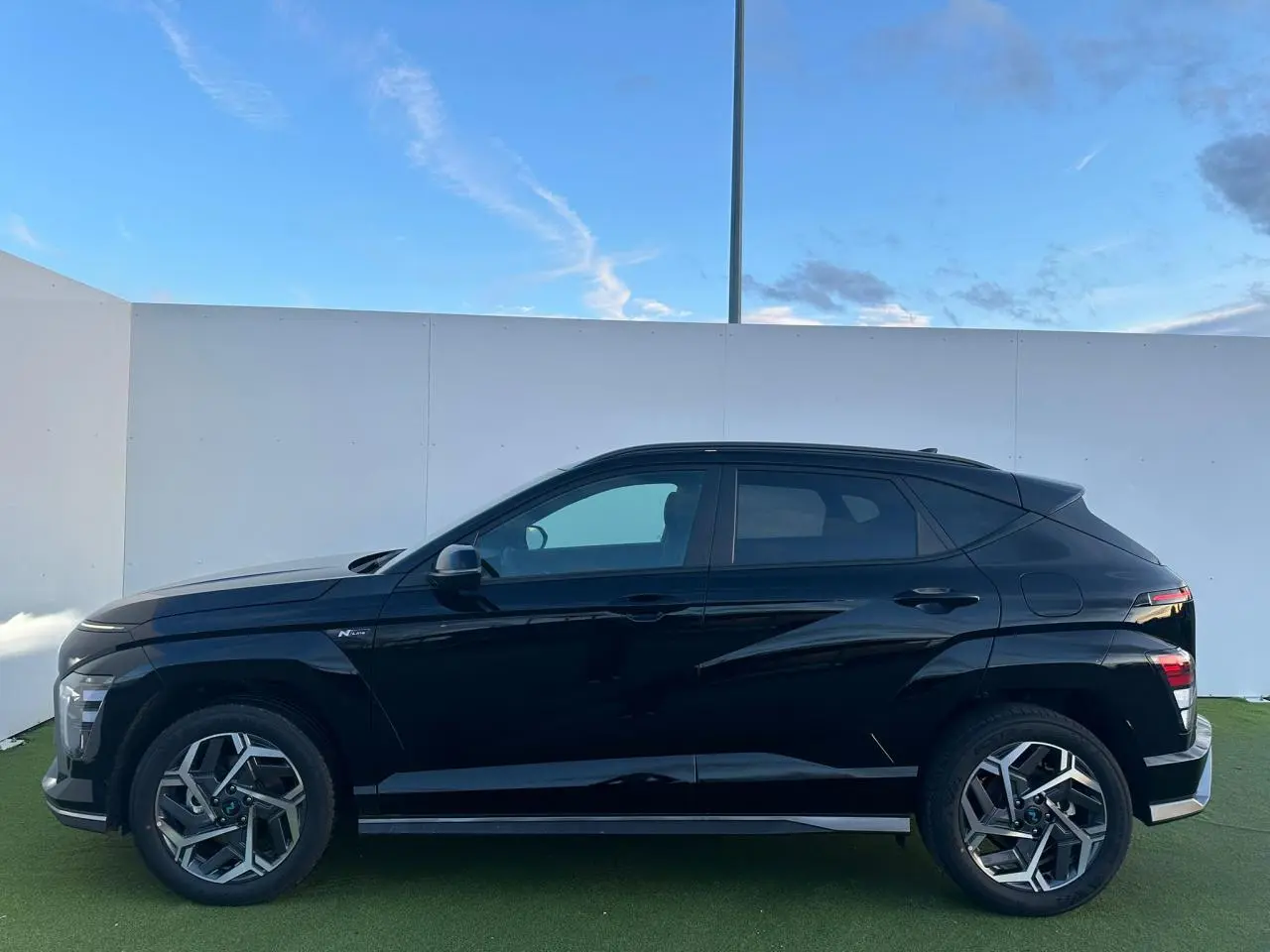 Vue de profil côté gauche du Hyundai Kona II noir Abyss Metal avec jantes alliage 18 pouces et détails N Line.