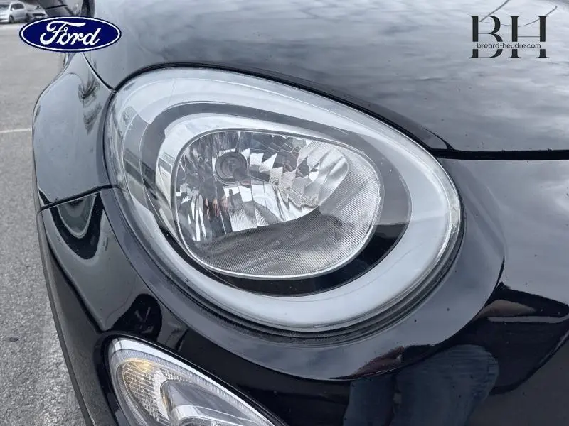 Gros plan sur le phare avant gauche d'une FIAT 500X noire Cinéma pastel, mettant en valeur son design arrondi distinctif.