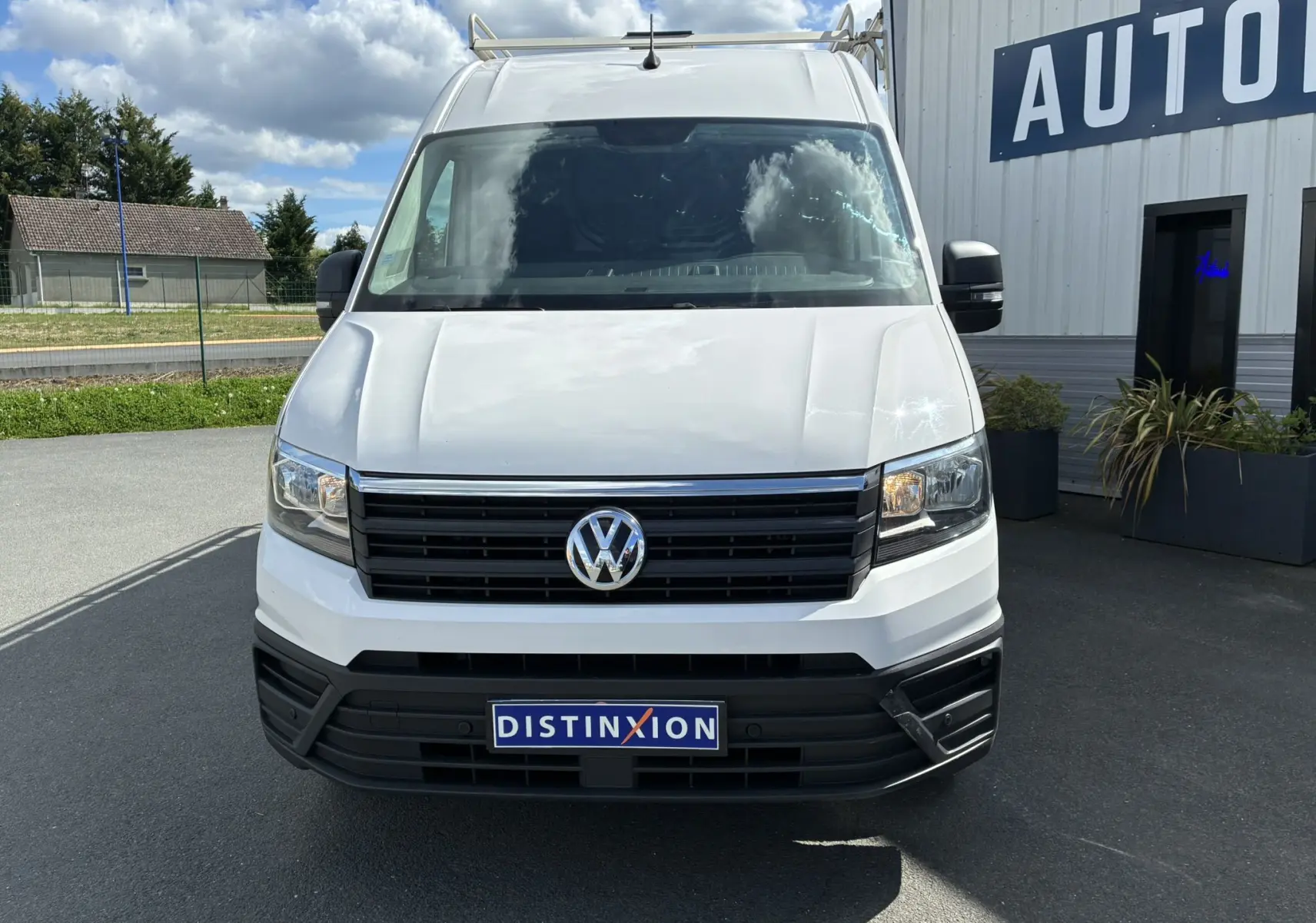 Vue frontale d'un Volkswagen Crafter blanc avec calandre noire et plaque Distinxion visible.