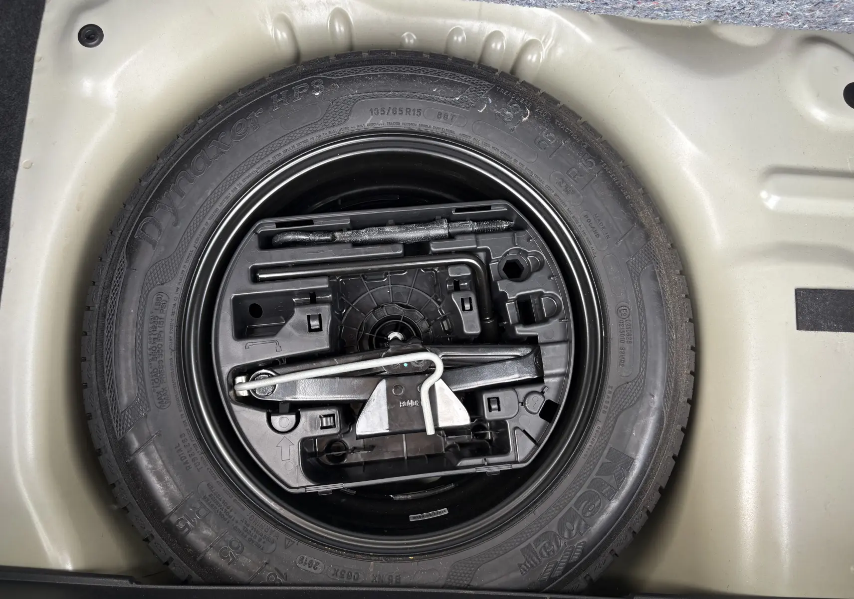 Vue plongeante sur la roue de secours noire et beige avec outils intégrés du Citroën C3 2019 beige.
