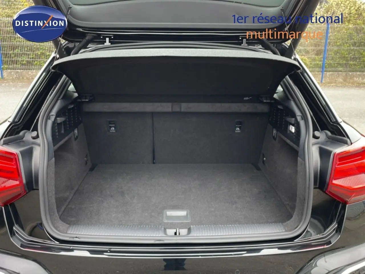 Coffre ouvert vu de l'arrière d'un Audi Q2 noir mito metal, avec banquette arrière rabattue et intérieur spacieux.
