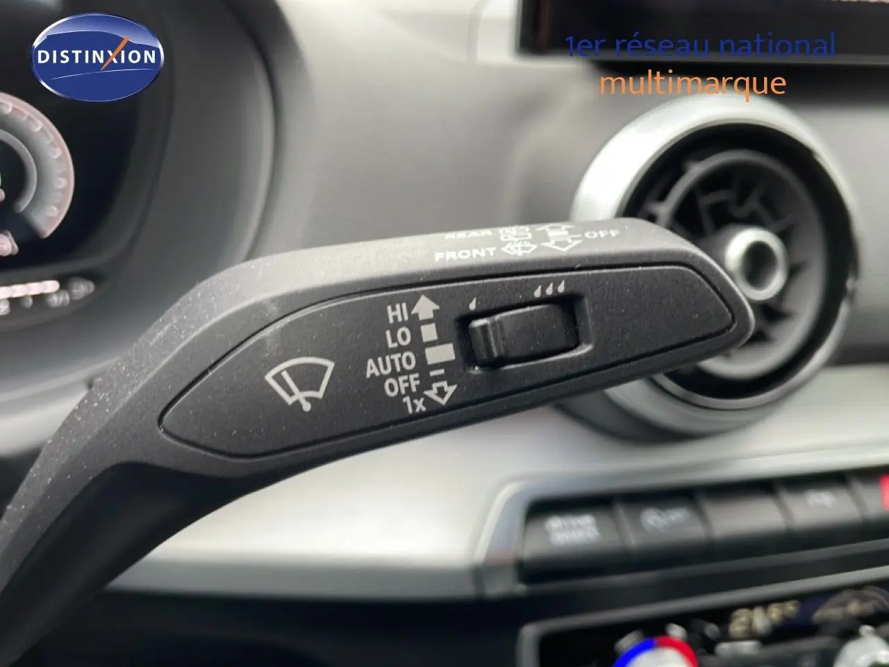 Gros plan sur la commande d’essuie-glace dans l’habitacle d’un Audi Q2 noir mito metal, avec tableau de bord et aérateurs visibles.