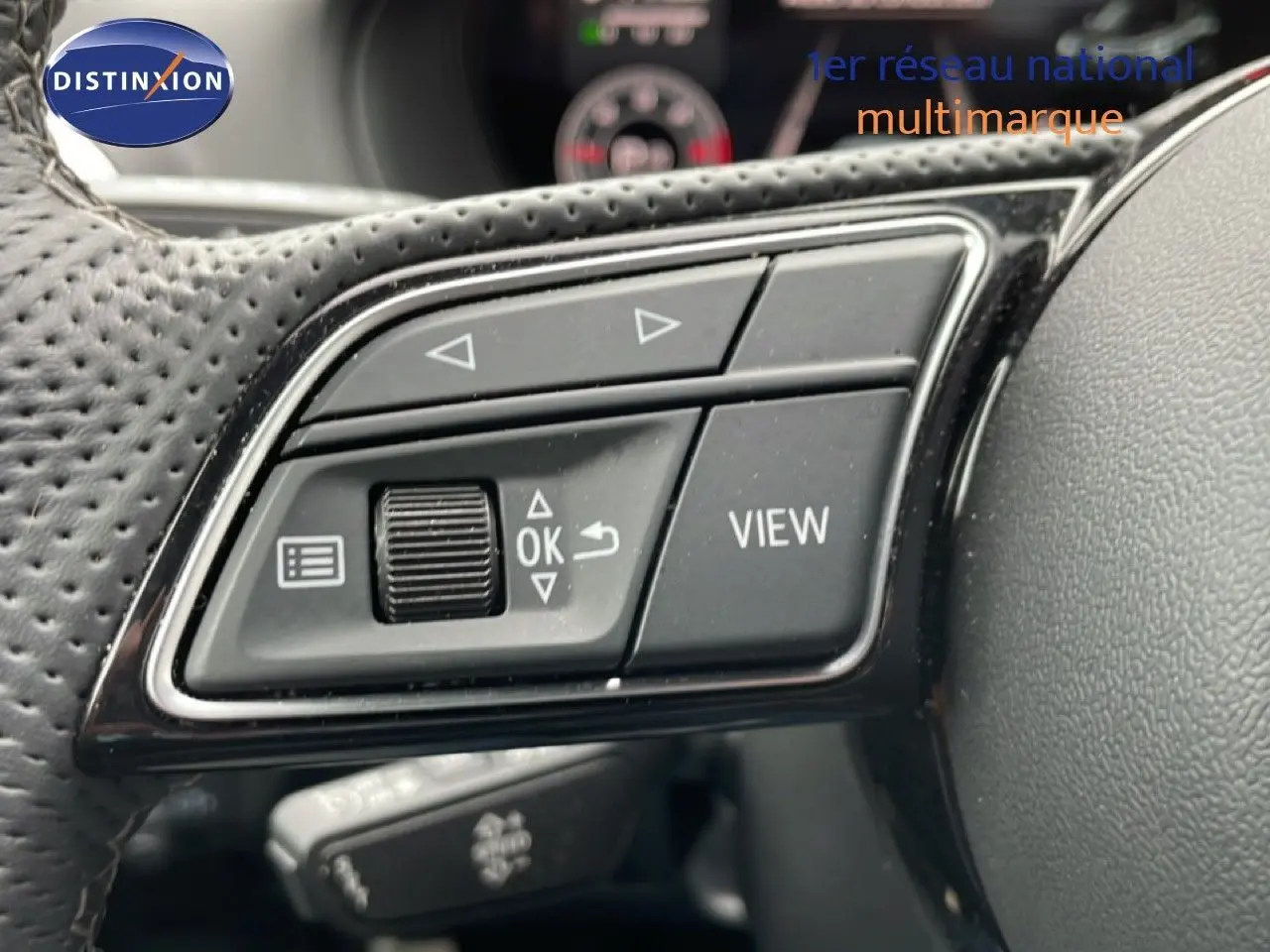 Gros plan sur les commandes multifonctions noires du volant perforé de l'Audi Q2 2025, finition S-Line.