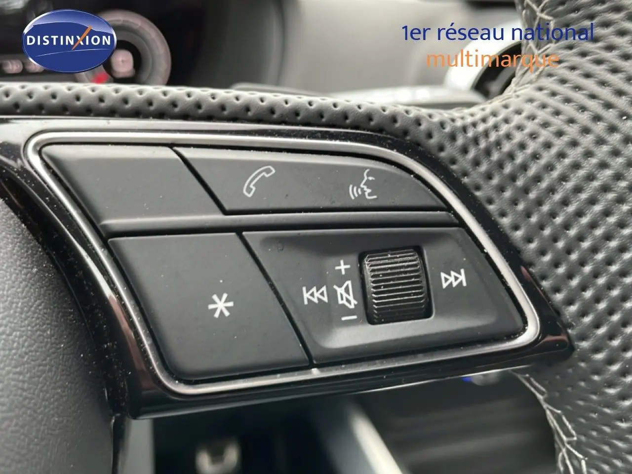 Gros plan sur les commandes multifonctions en cuir perforé du volant de l'Audi Q2 noir mito metal, côté gauche.