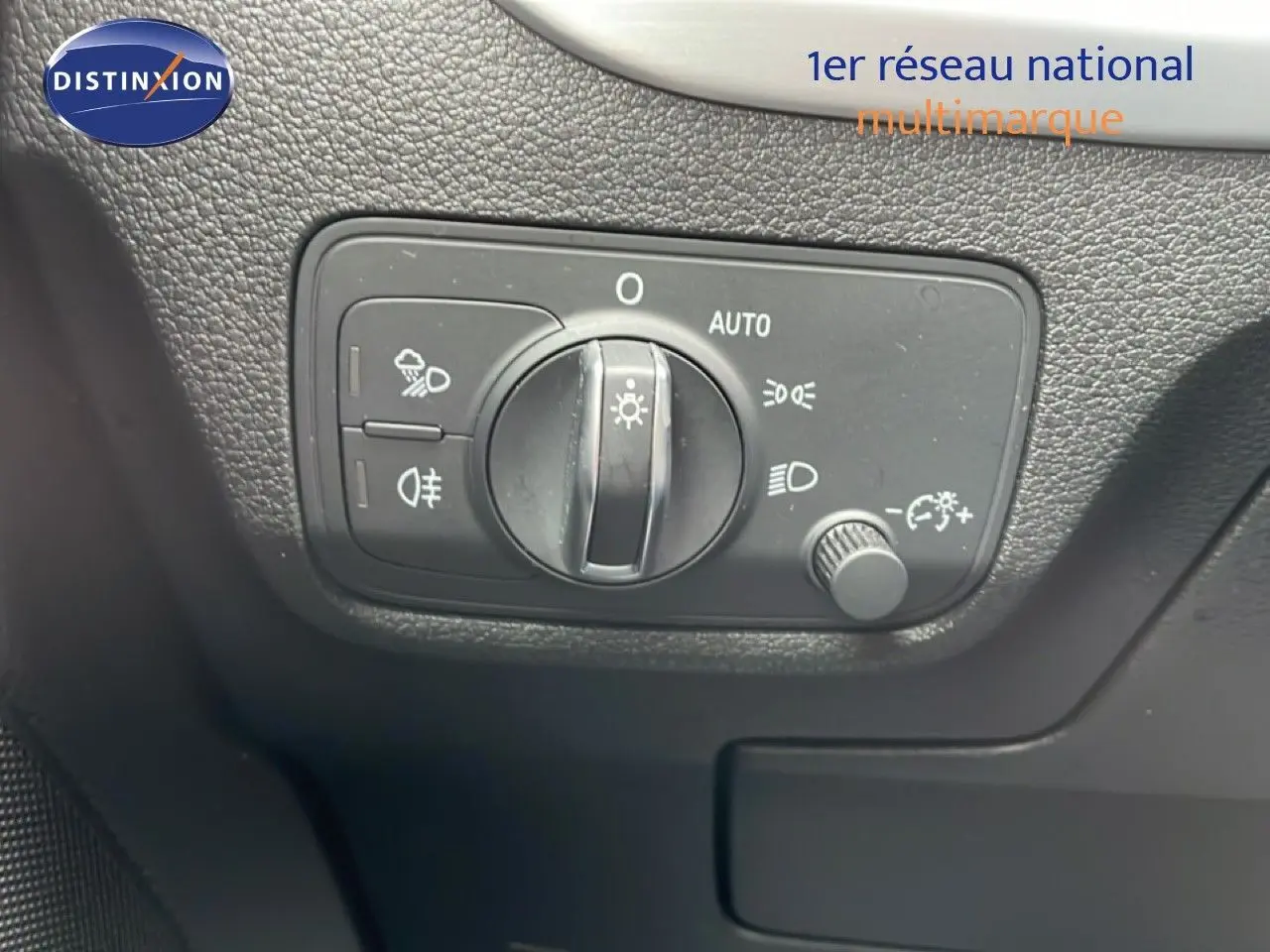 Gros plan sur le bouton de commande des phares de l’Audi Q2 noir mito metal, intérieur avec surface texturée noire.