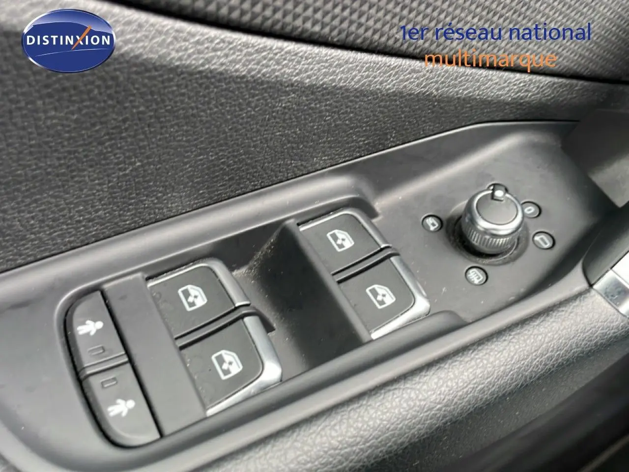 Gros plan sur les commandes des vitres et rétroviseurs côté conducteur de l'Audi Q2 noir mito metal, intérieur noir.