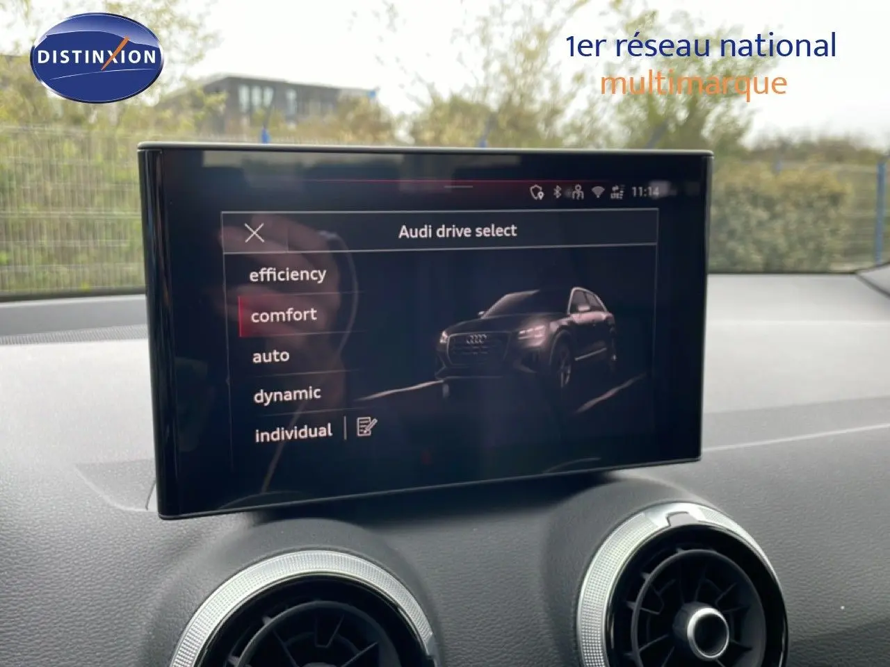 Écran central affichant le menu Audi drive select avec options de conduite, intérieur noir du Q2 visible en arrière-plan.