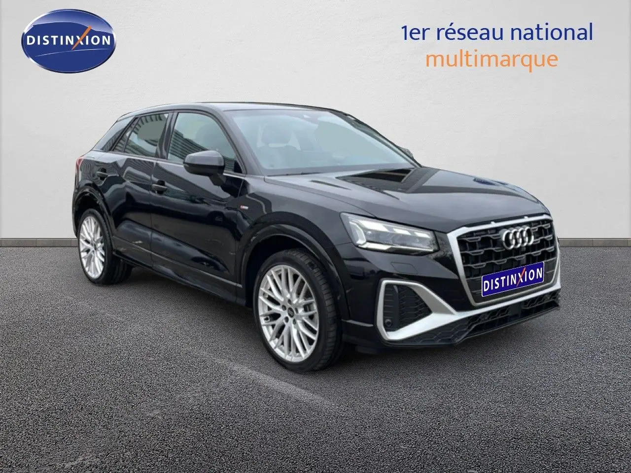 Audi Q2 noir mito metal en 3/4 avant droit, avec jantes alliage et calandre hexagonale distinctive S-Line.