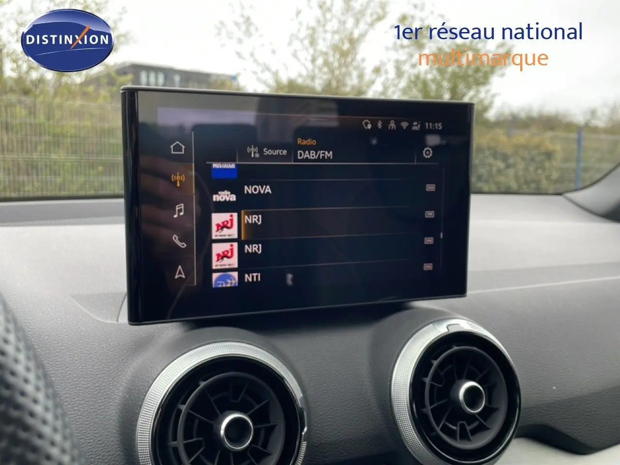 Écran tactile central affichant les radios DAB/FM, avec les aérateurs ronds du tableau de bord d’un Audi Q2 noir Mito Metal.