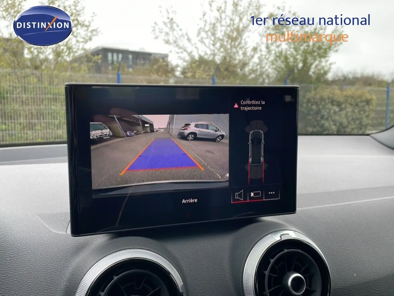 Écran central montrant la caméra de recul de l'Audi Q2 noire, avec guidage de trajectoire visible.