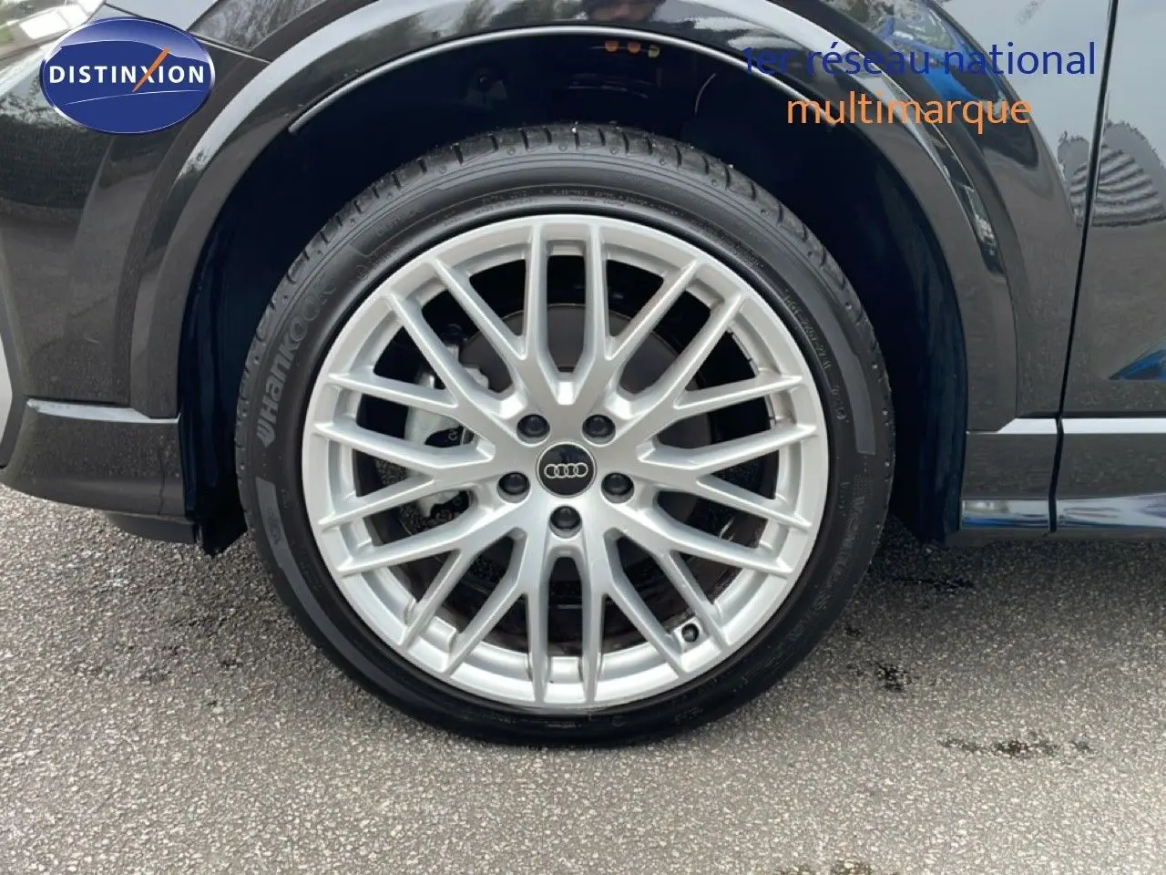 Gros plan sur la roue avant gauche de l'Audi Q2 noir mito metal avec jante alliage multibranches argentée.