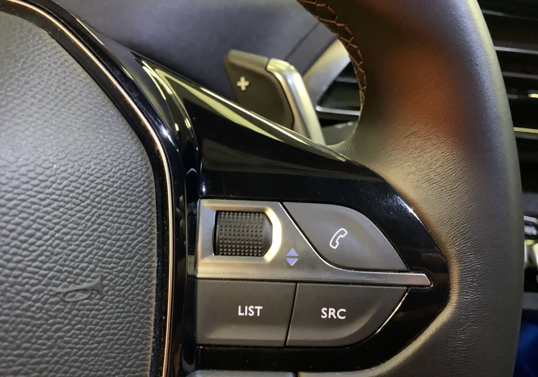Gros plan sur les commandes gauche du volant du Peugeot 5008 Bleu Célèbes, avec molette et boutons fonction audio.