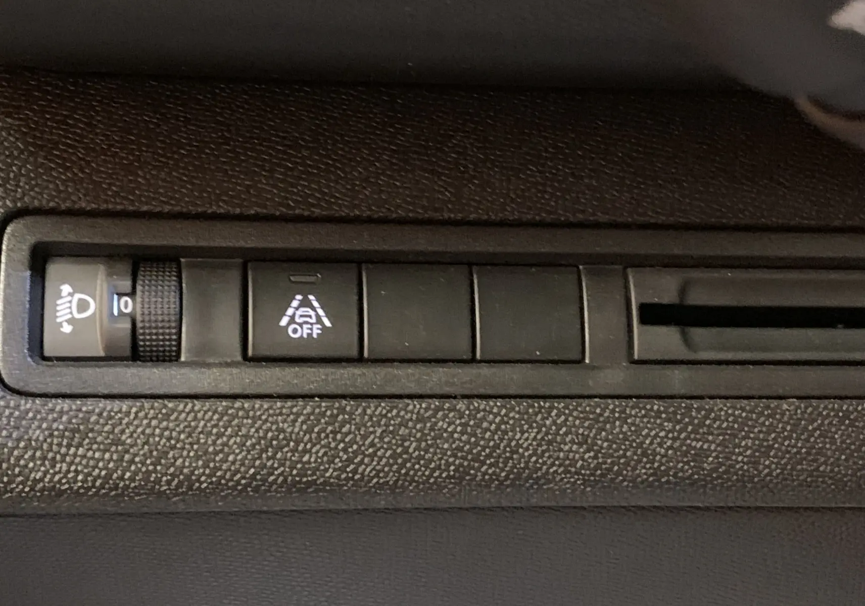 Gros plan sur les commandes d'assistance à la conduite et réglage des phares du Peugeot 5008 Bleu Célèbes, intérieur noir.