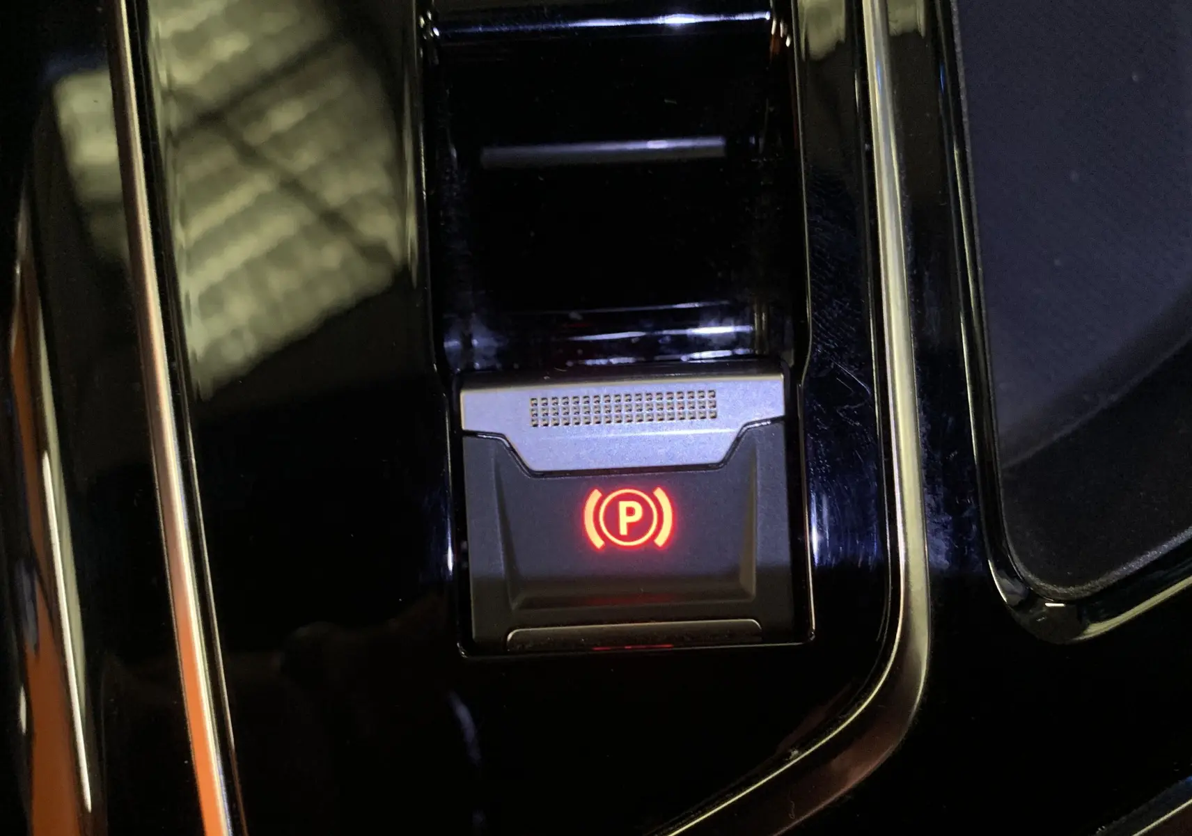 Bouton de frein de parking électronique éclairé en rouge sur la console centrale noire du Peugeot 5008 Bleu Célèbes.