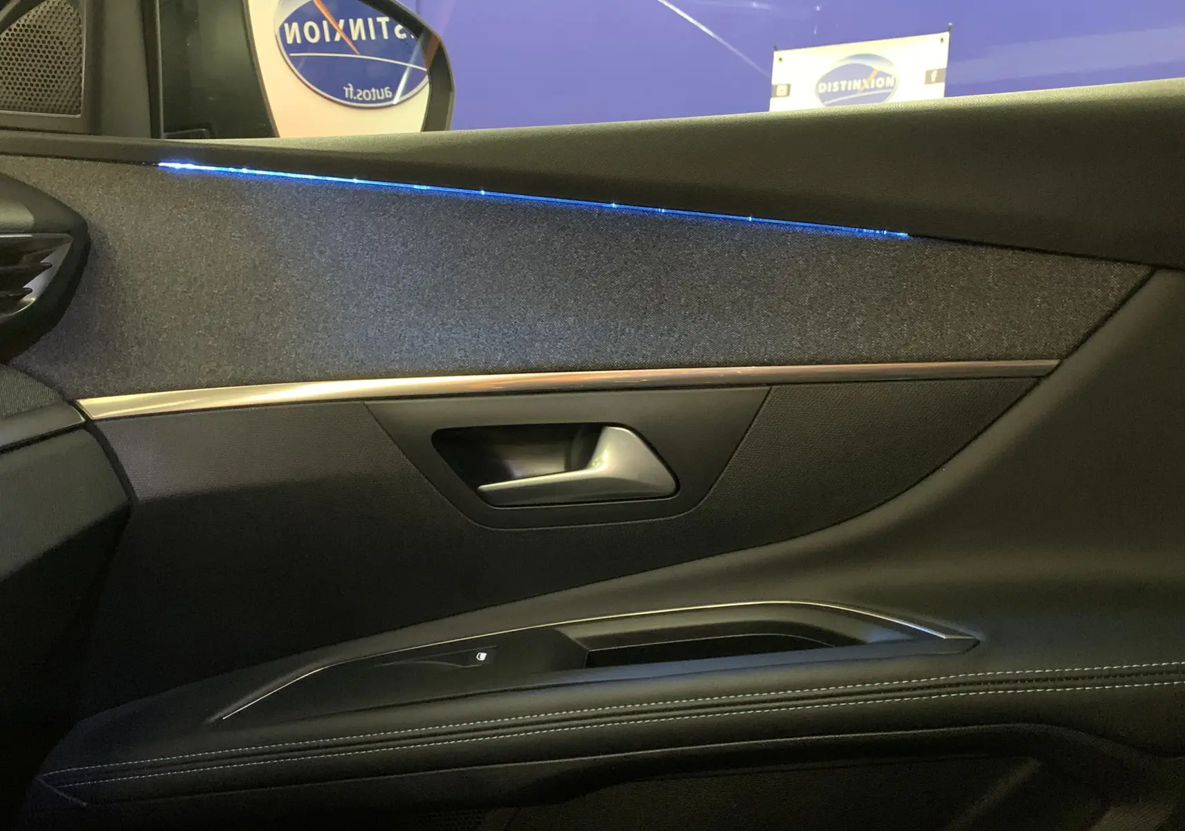 Détail de la porte côté gauche du Peugeot 5008 2024 avec éclairage d'ambiance bleu et garniture noire.