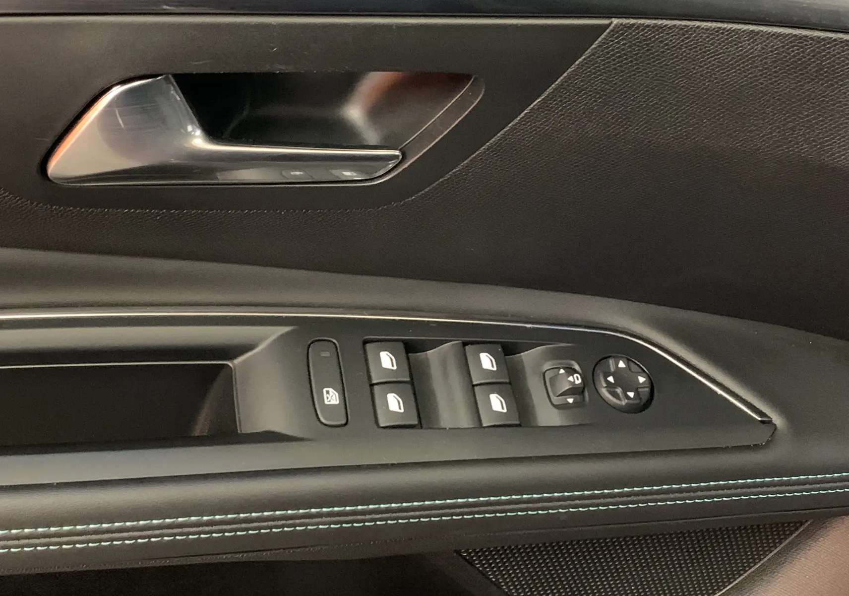 Gros plan sur la commande des vitres et rétroviseurs côté conducteur du Peugeot 5008 bleu, avec surpiqûres bleues visibles.