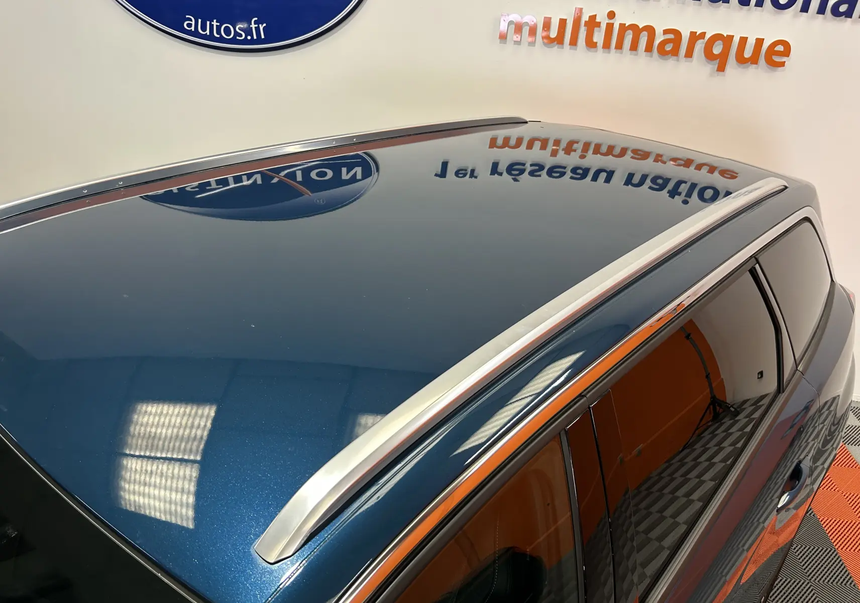 Vue en plongée du toit bleu célèbes du Peugeot 5008 avec barres de toit argentées et vitres teintées côté droit.