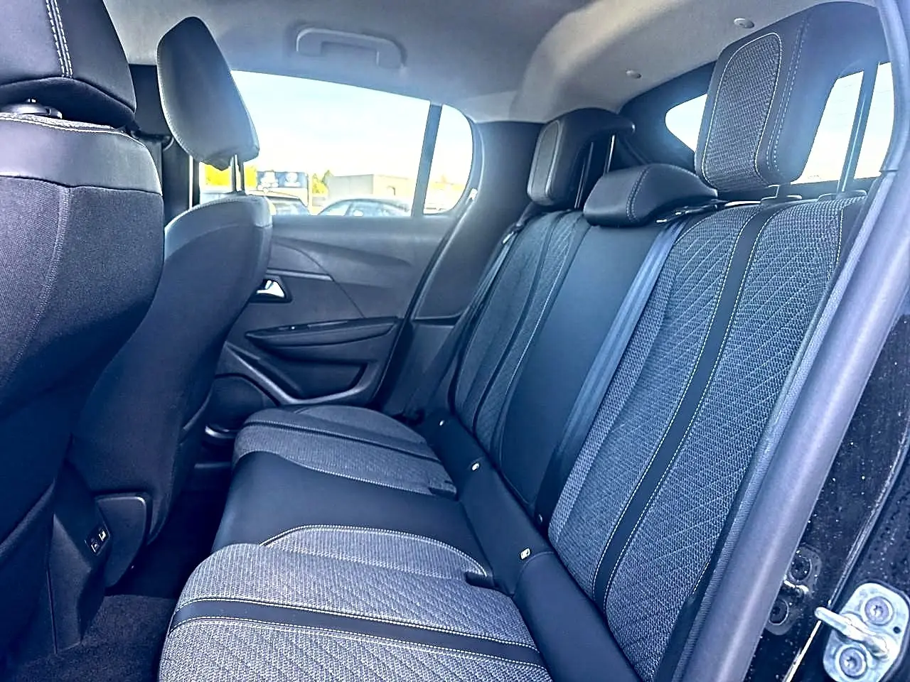 Vue intérieure côté droit sur la banquette arrière en tissu gris et noir de la Peugeot 208 1.2 100 Allure noire 2025.