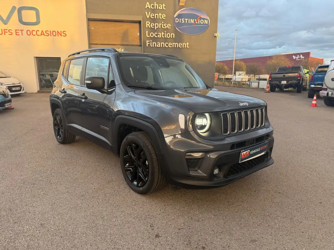 Jeep Renegade gris anthracite en 3/4 avant droit avec jantes alliage noires et barres de toit visibles.