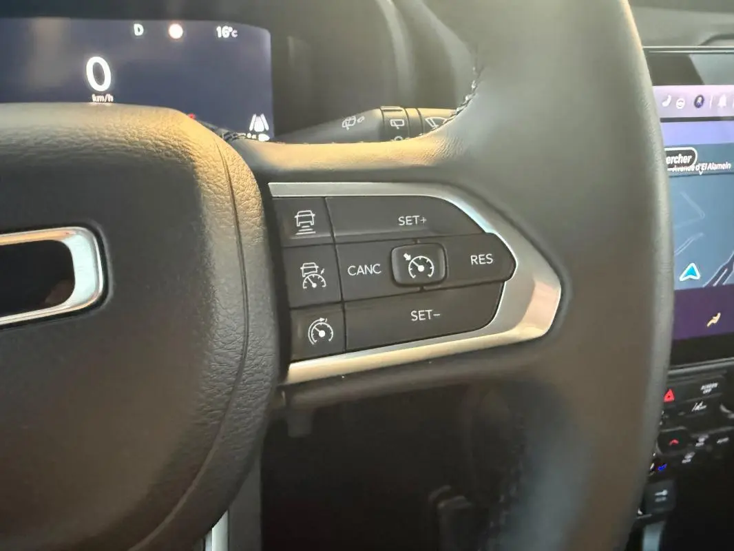 Gros plan sur les commandes du régulateur de vitesse au volant cuir noir du Jeep Renegade 2024 gris anthracite.