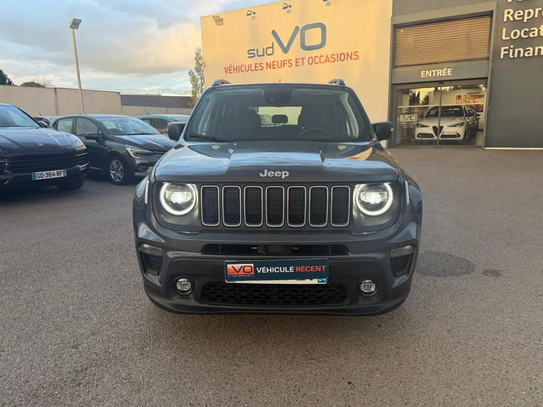 Vue frontale d'un Jeep Renegade gris anthracite 2024 avec phares allumés et barres de toit visibles.