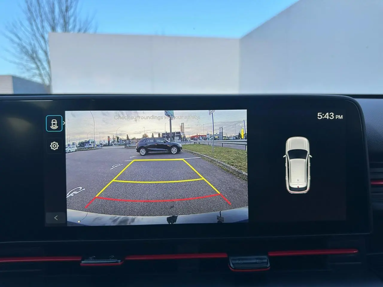 Rétroviseur droit noir brillant du Hyundai Kona II 1.6 Hybrid 138 N Line en Ecotronic Grey, reflet du ciel nuageux visible.