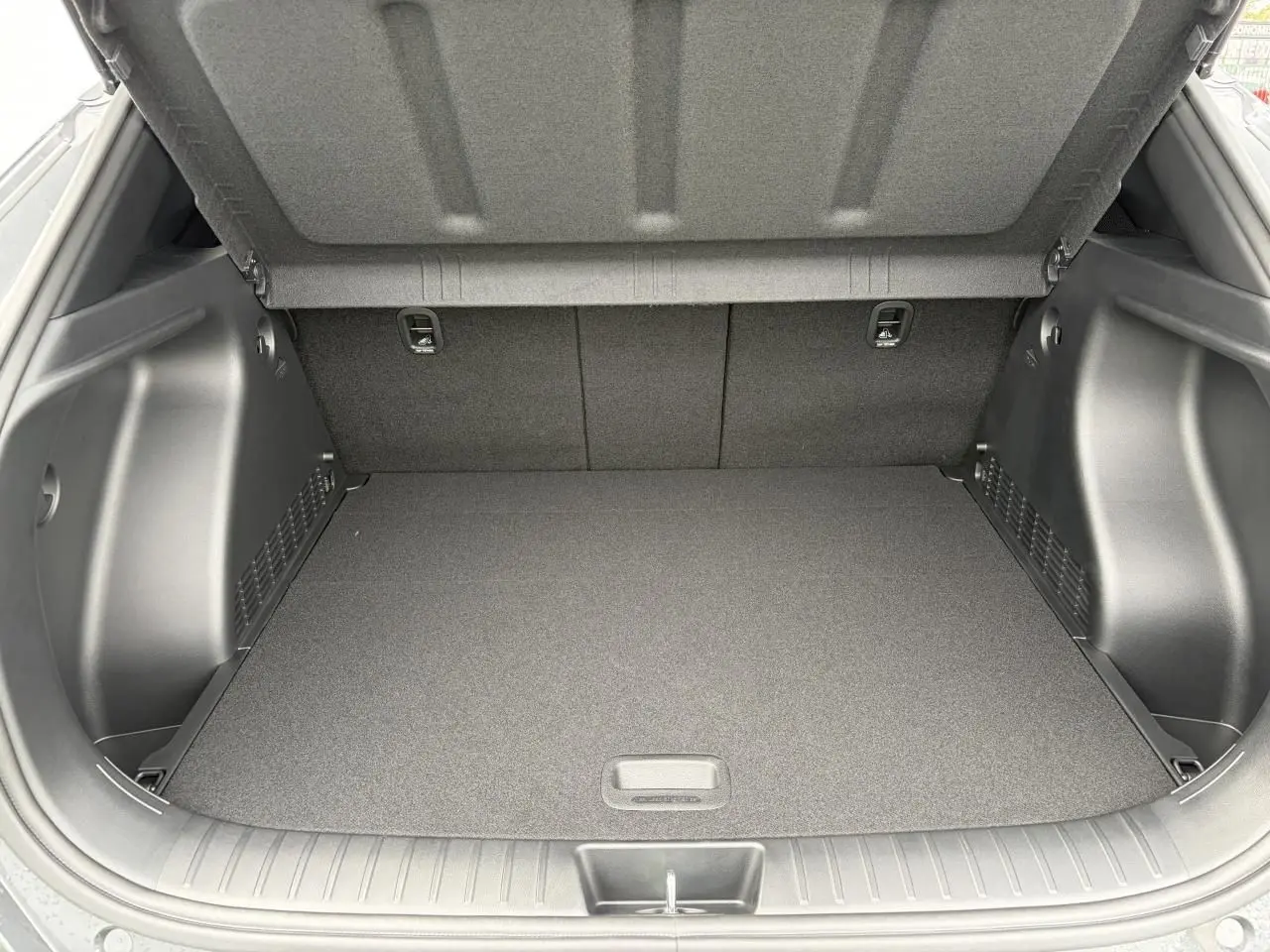 Coffre ouvert vu de l'arrière du Hyundai Kona II 1.6 Hybrid N Line gris Ecotronic, montrant un espace de chargement propre et spacieux.