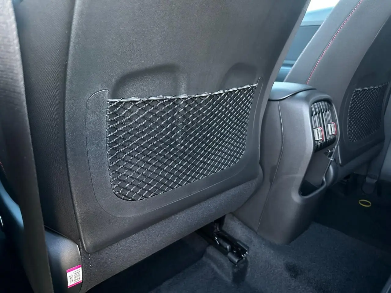 Détail de l’arrière des sièges avant noirs avec filet de rangement et prises d’aération au centre du Hyundai Kona 2026.