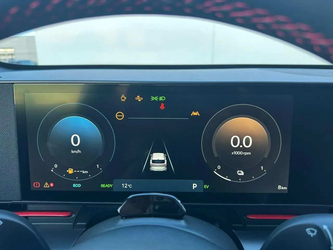 Hyundai Kona II 1.6 Hybrid N Line gris Ecotronic en 3/4 avant droit sur sol vert avec calandre noire distinctive.