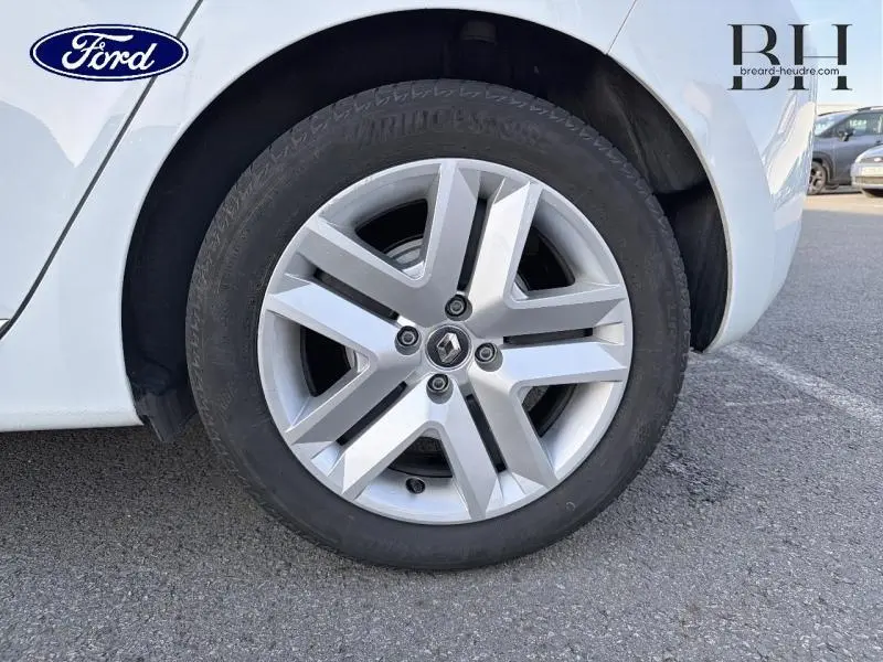 Gros plan sur la roue avant droite blanche d'une Renault Clio 1.6 E-Tech 140ch Business avec jante alliage distinctive.