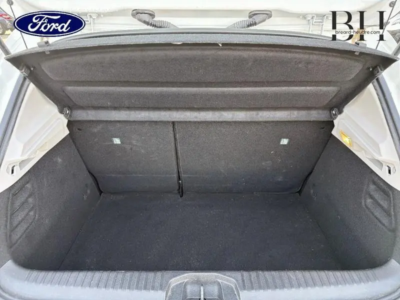 Coffre ouvert vu de face d'une Renault Clio blanche, montrant l'espace de chargement vide et la tablette cache-bagages.