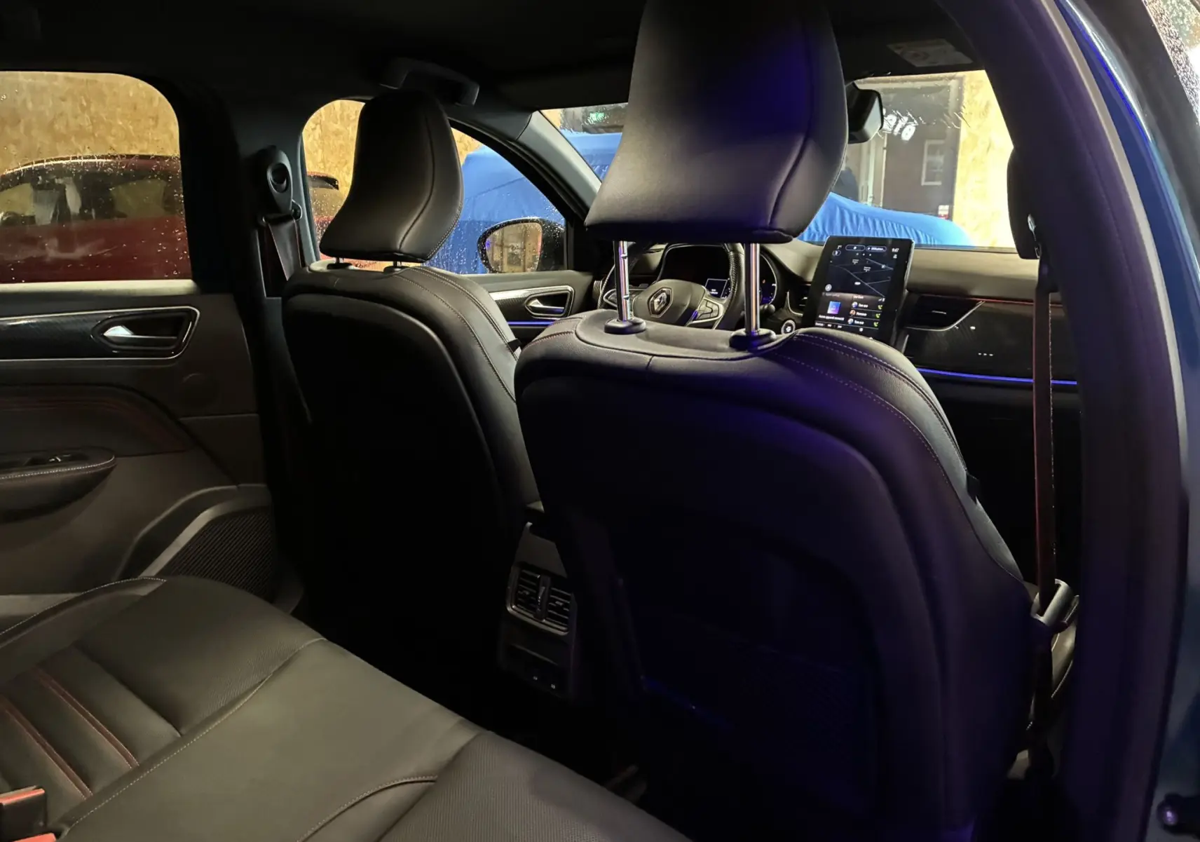 Vue intérieure arrière du Renault Arkana bleu 2021, mettant en valeur les sièges cuir noirs et l'écran tactile central.