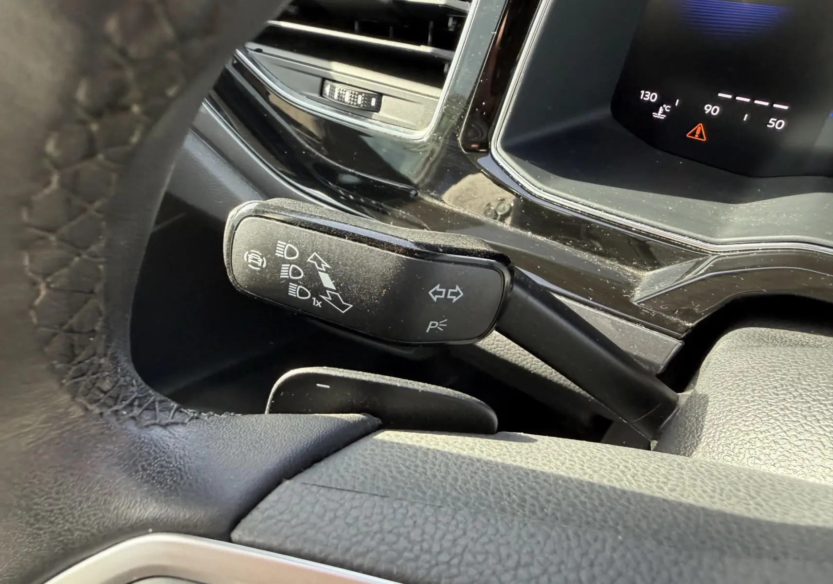 Gros plan sur la manette de clignotants côté gauche du volant dans l'habitacle noir d'une Volkswagen Polo 2025.