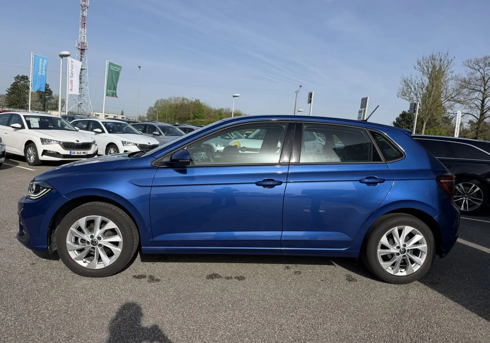 Vue de profil côté gauche d'une Volkswagen Polo 2025 bleu récif métallisé avec jantes alliage 16 pouces sur parking extérieur.