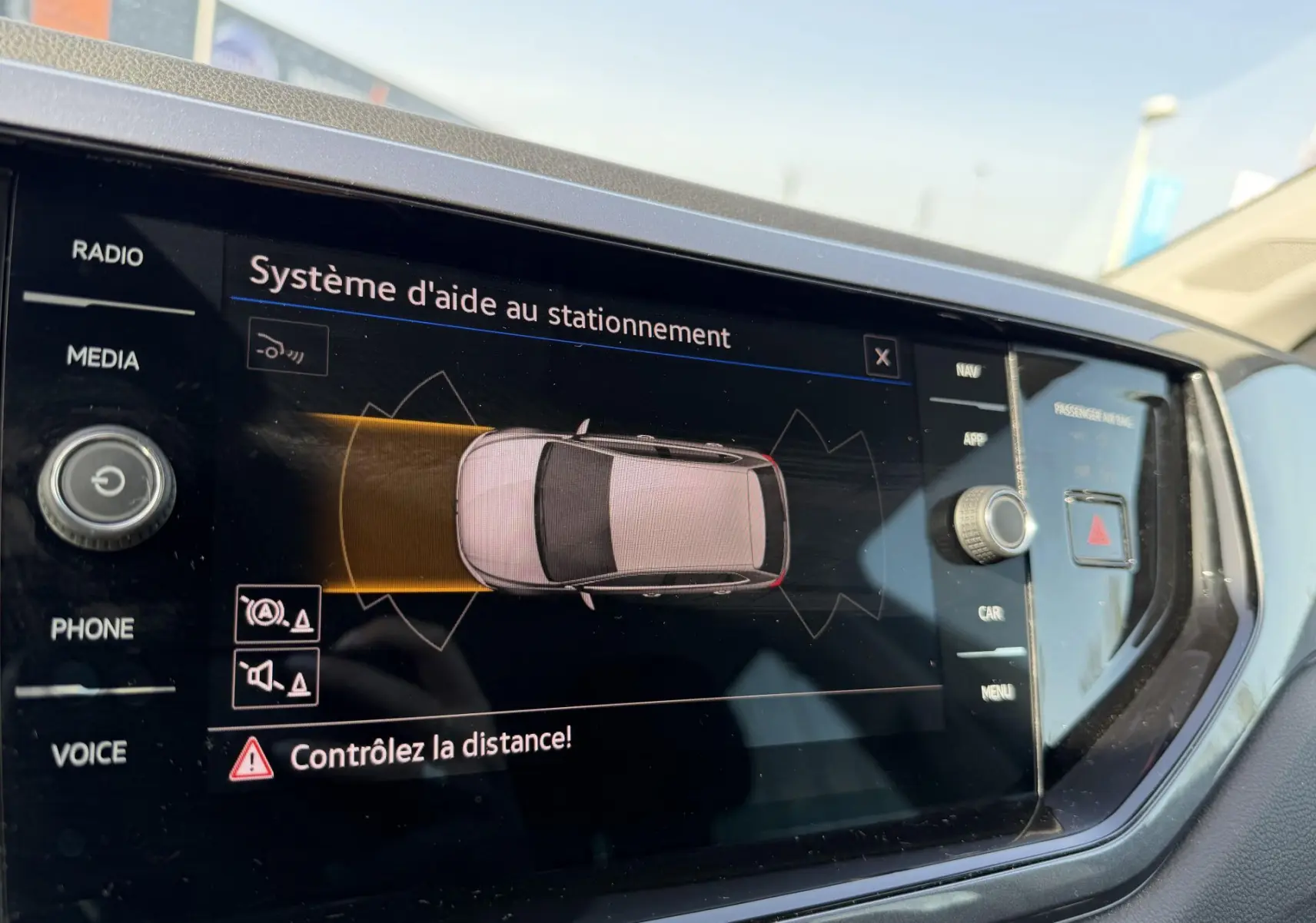 Écran tactile intérieur montrant le système d'aide au stationnement de la Volkswagen Polo bleue, vue de près côté conducteur.