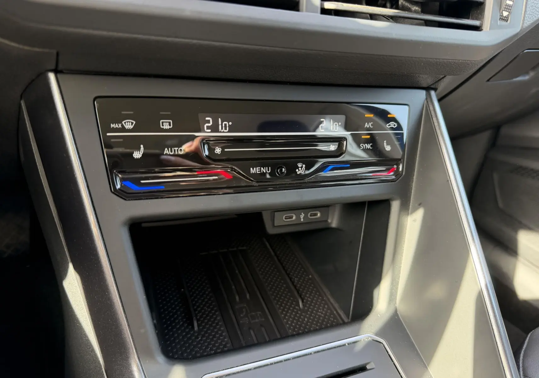 Vue rapprochée de la console centrale de la Volkswagen Polo bleue, montrant la climatisation tactile bi-zone et ports USB-C.