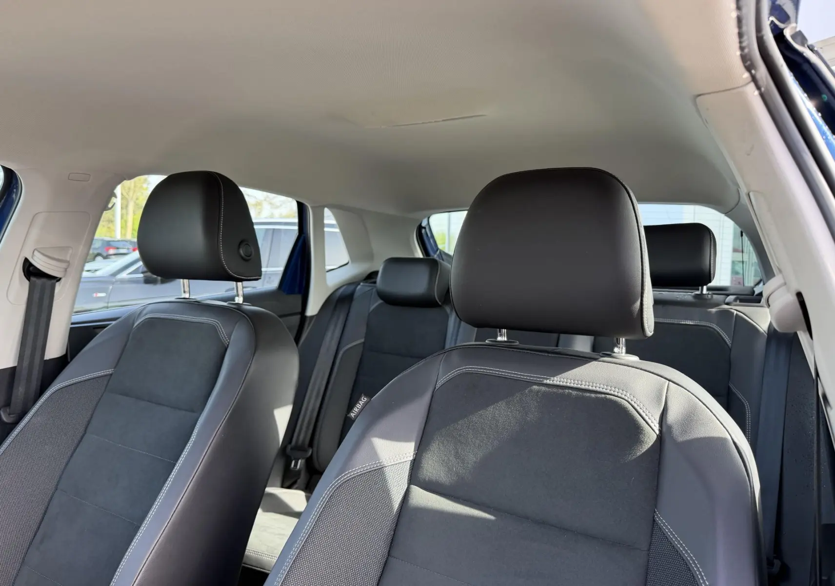Vue intérieure des sièges avant et arrière en tissu et cuir noir de la Volkswagen Polo 2025, porte ouverte côté droit.