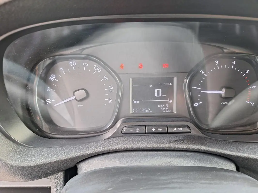 Vue rapprochée du tableau de bord du fourgon Opel Vivaro blanc, affichant compteur et écran digital.