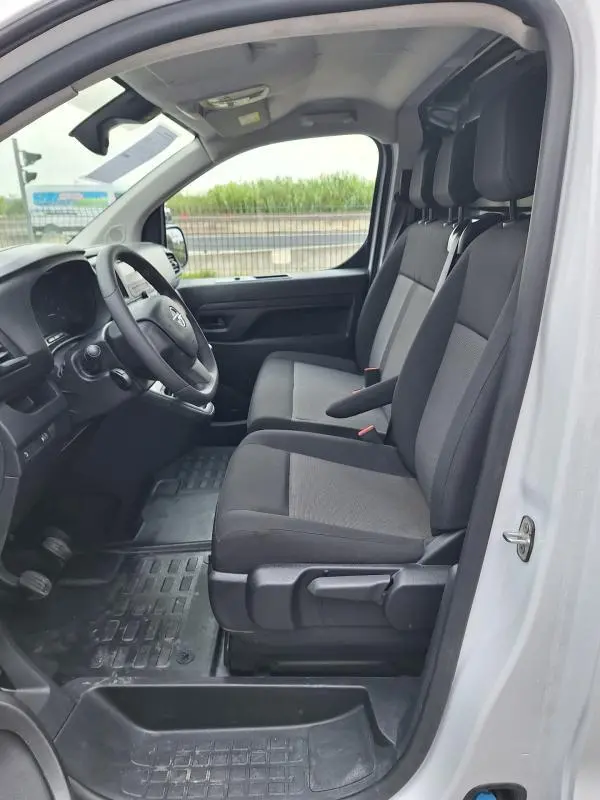 Vue intérieure côté conducteur de l'Opel Vivaro blanc 2025, montrant les sièges avant et le volant réglable.