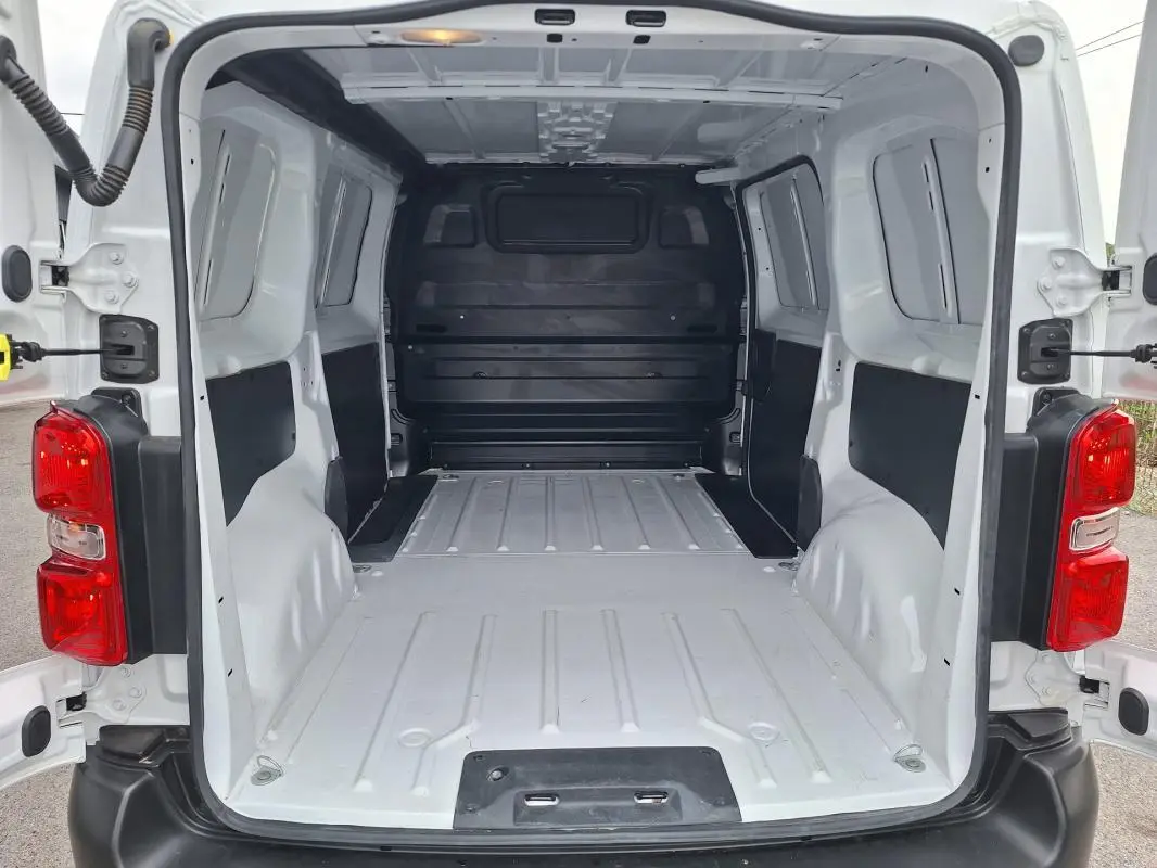 Vue arrière ouverte du fourgon blanc Opel Vivaro 2025, montrant l’espace de chargement vide et les feux arrière rouges.