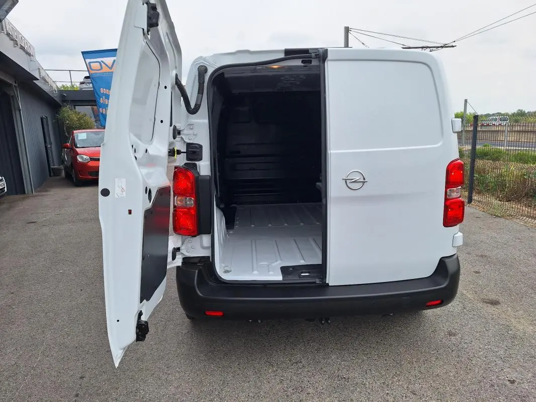 Vue arrière d’un Opel Vivaro blanc 2025 avec porte latérale ouverte montrant l’espace de chargement vide.