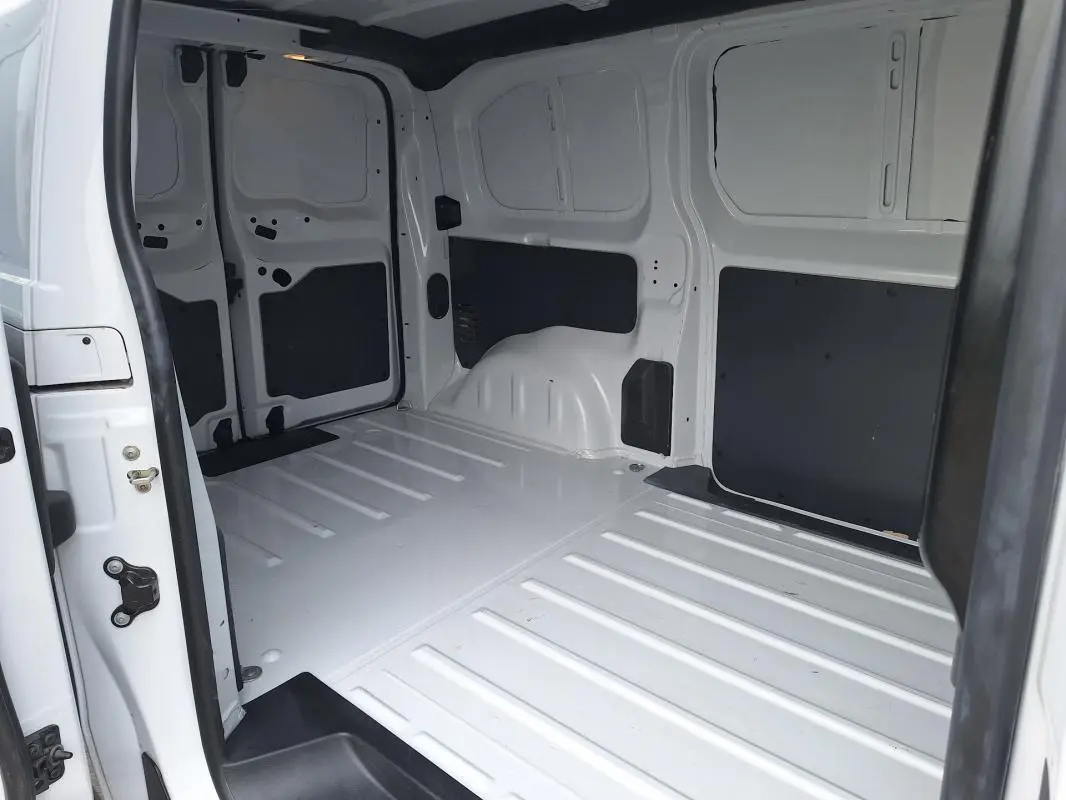 Vue intérieure du fourgon blanc Opel Vivaro 2025, montrant l'espace de chargement vide avec porte latérale ouverte.