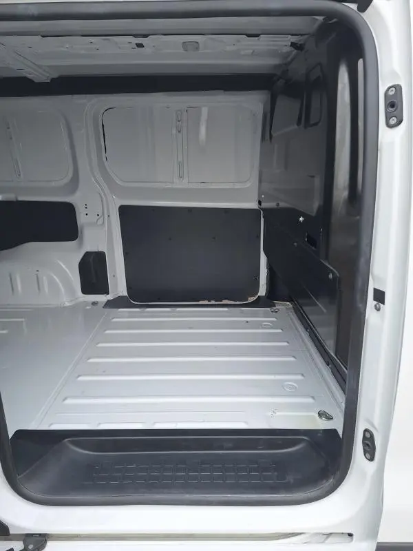 Vue intérieure de la zone de chargement du fourgon Opel Vivaro blanc, avec porte latérale ouverte et plancher métallique.
