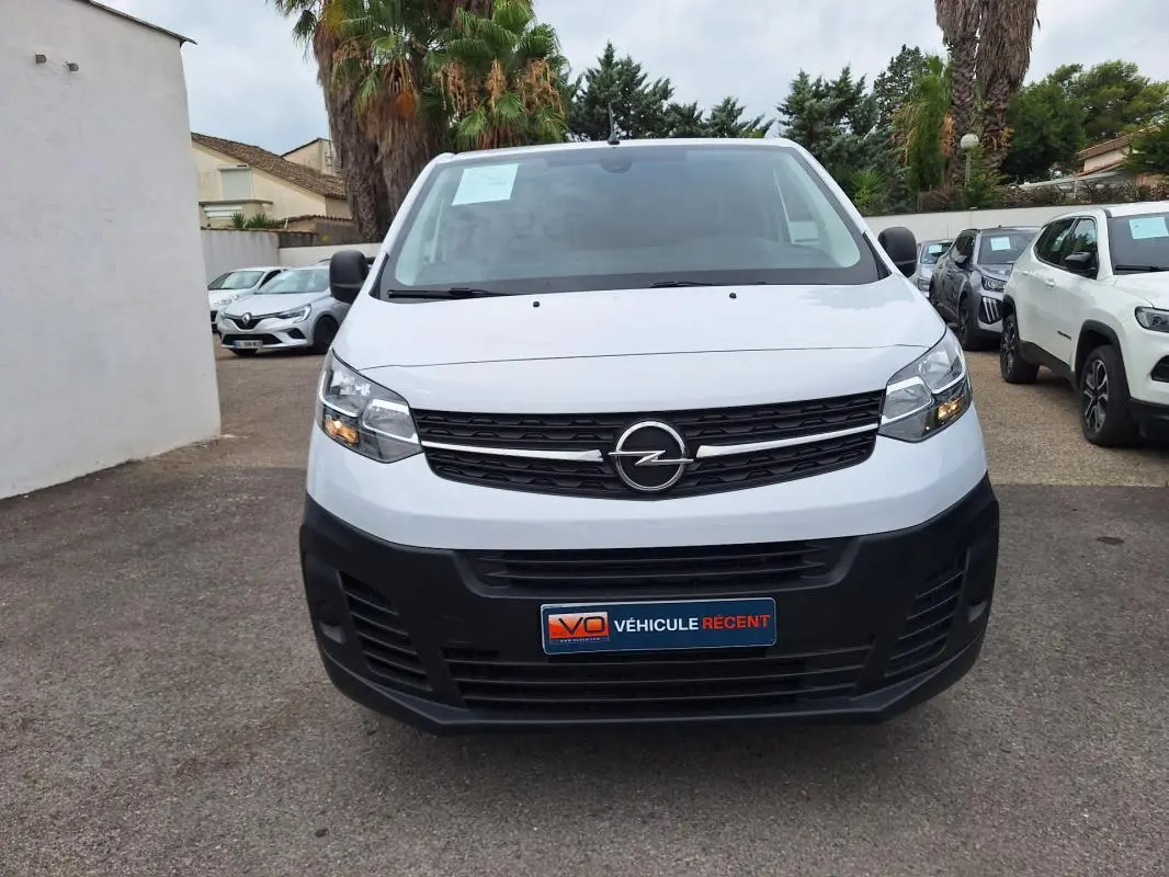 Vue frontale d’un Opel Vivaro blanc 2025 avec calandre noire et pare-chocs avant noir mat, en extérieur.